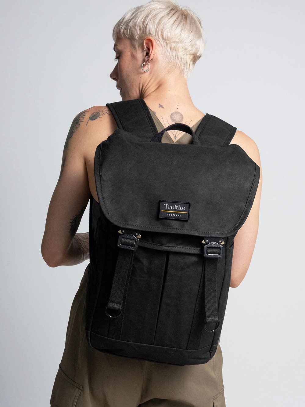 A female model is wearing the Trakke Bannoch Backpack in Black. The Bannoch is the COBRA variant
