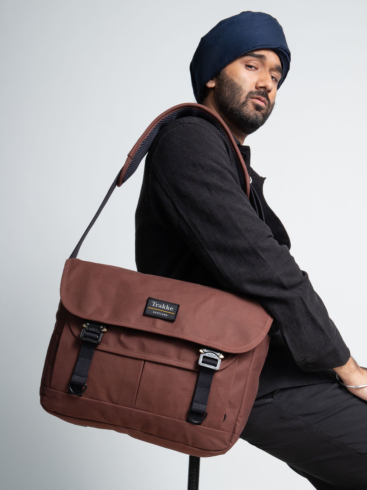 a man sitting on a stool with the bairn pro messenger in port colour