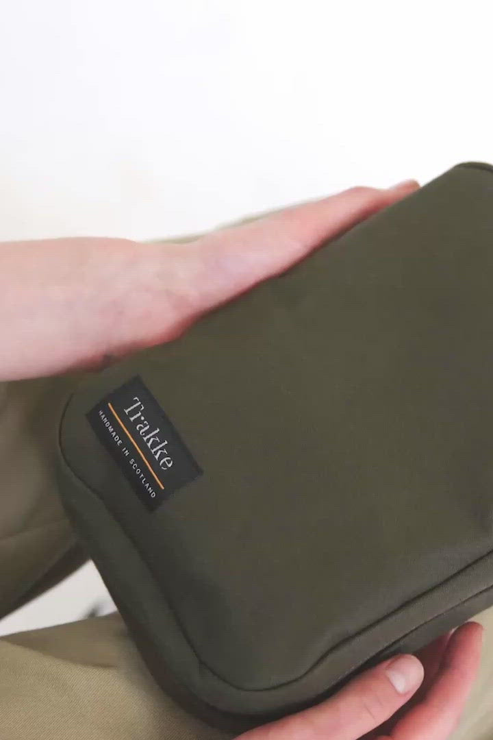 Video of a person opening the Trakke Laggan Pro in Olive showing the interior which is comprised of four looped sections of black elastic, a zip compartment and pockets on either side. Elastic is also in the spine interior to fit pens and pencils, for example.